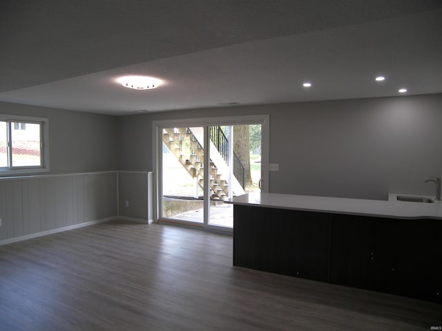 empty room with wainscoting, plenty of natural light, a sink, and wood finished floors