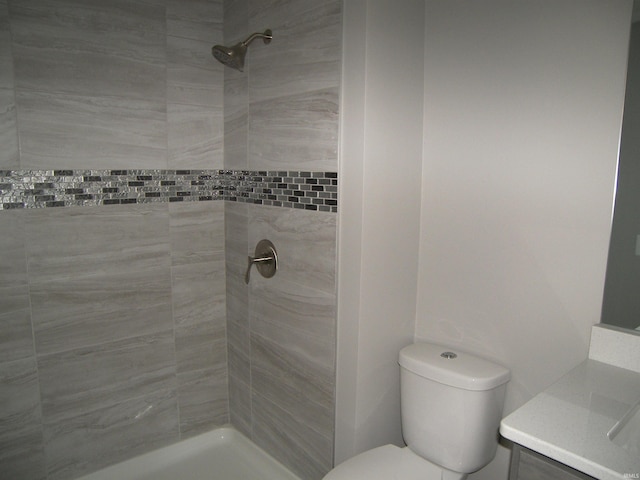 bathroom featuring tiled shower, vanity, and toilet