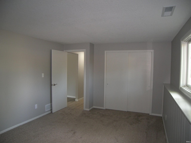 unfurnished bedroom featuring light carpet, a closet, visible vents, and baseboards