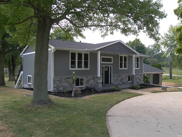 split foyer home featuring a front yard, stone siding, and covered porch