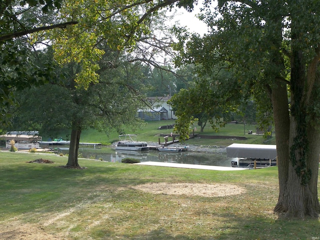 view of home's community featuring a dock, a water view, and a lawn