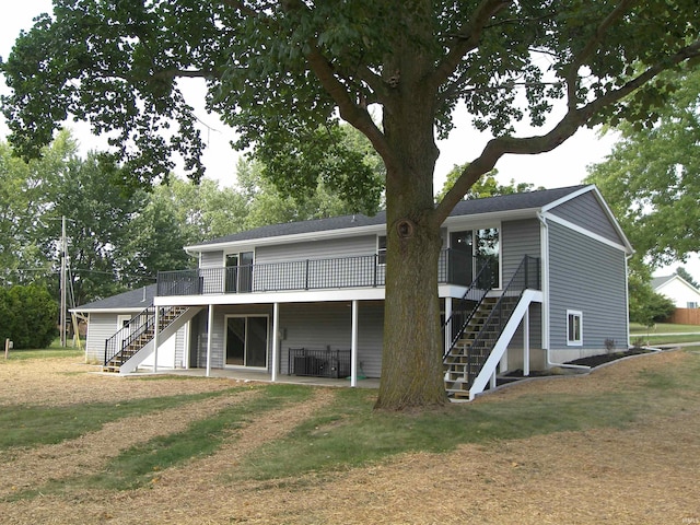 back of house featuring a lawn, stairway, and a wooden deck