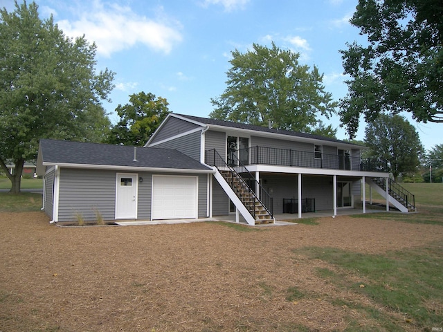 view of front of house featuring a deck, an attached garage, stairs, driveway, and a front lawn