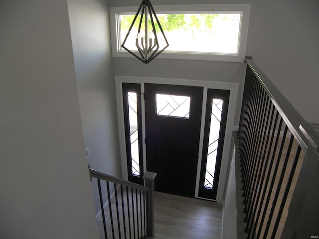 entryway featuring a notable chandelier, stairway, and wood finished floors