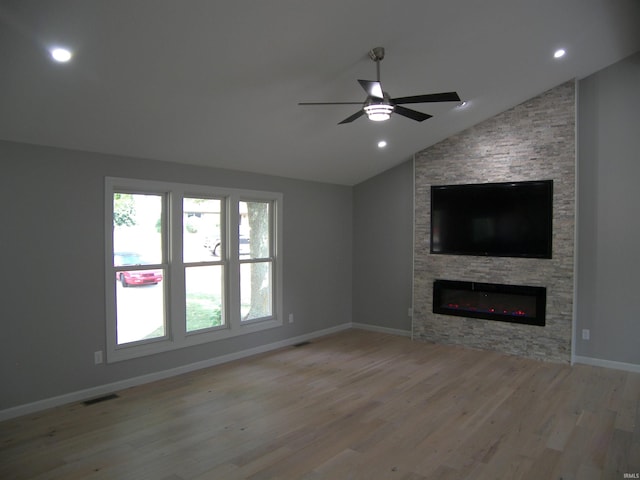 unfurnished living room with baseboards, visible vents, lofted ceiling, wood finished floors, and a fireplace