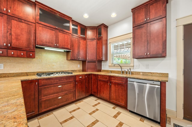 kitchen with light stone counters, stainless steel appliances, sink, and tasteful backsplash