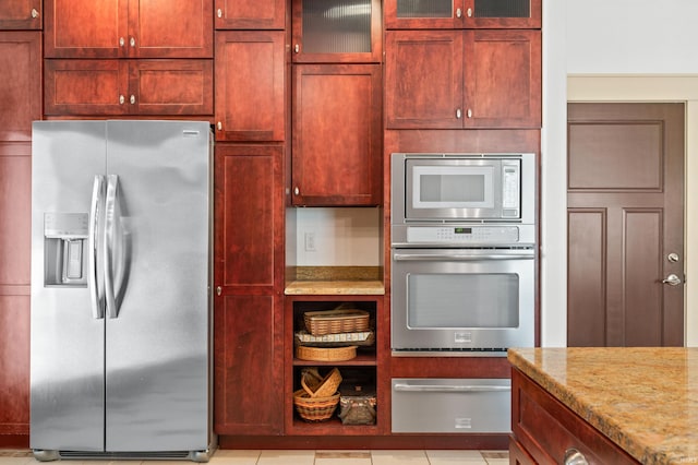 kitchen with appliances with stainless steel finishes, light stone countertops, and light tile patterned flooring