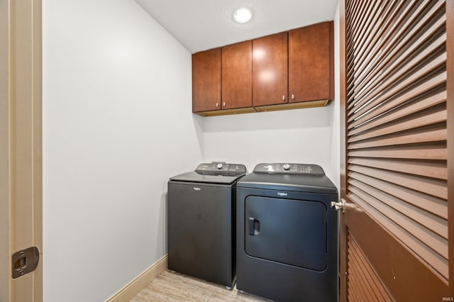 clothes washing area with washing machine and clothes dryer and cabinets