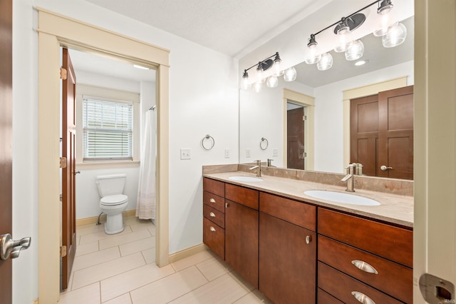 bathroom featuring tile patterned floors, toilet, a textured ceiling, and vanity