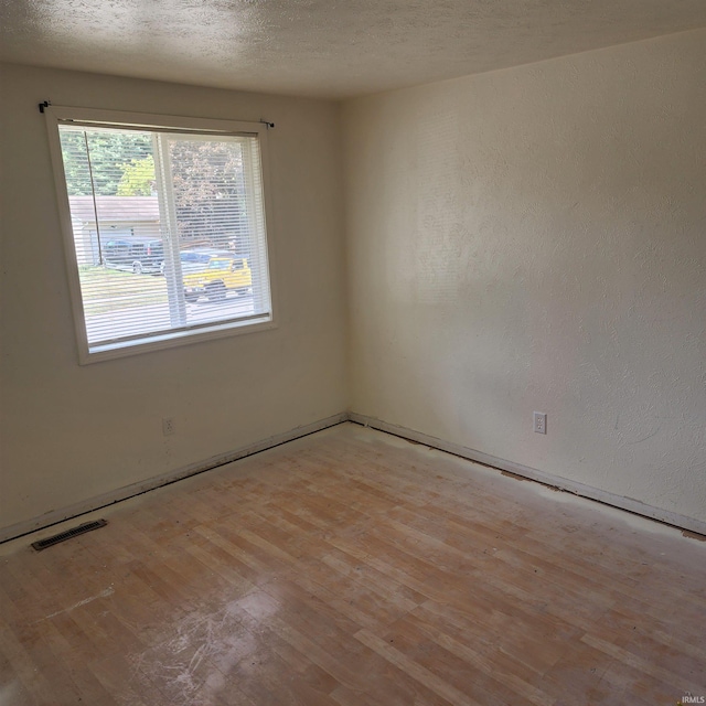 spare room featuring a textured ceiling and hardwood / wood-style floors