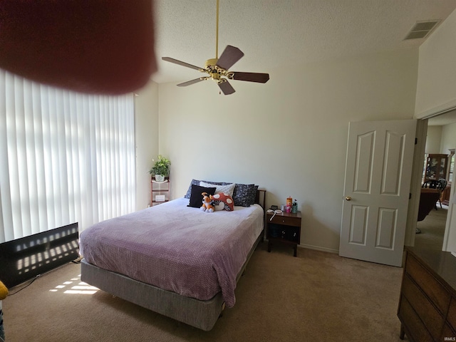 carpeted bedroom with a textured ceiling, ceiling fan, and vaulted ceiling