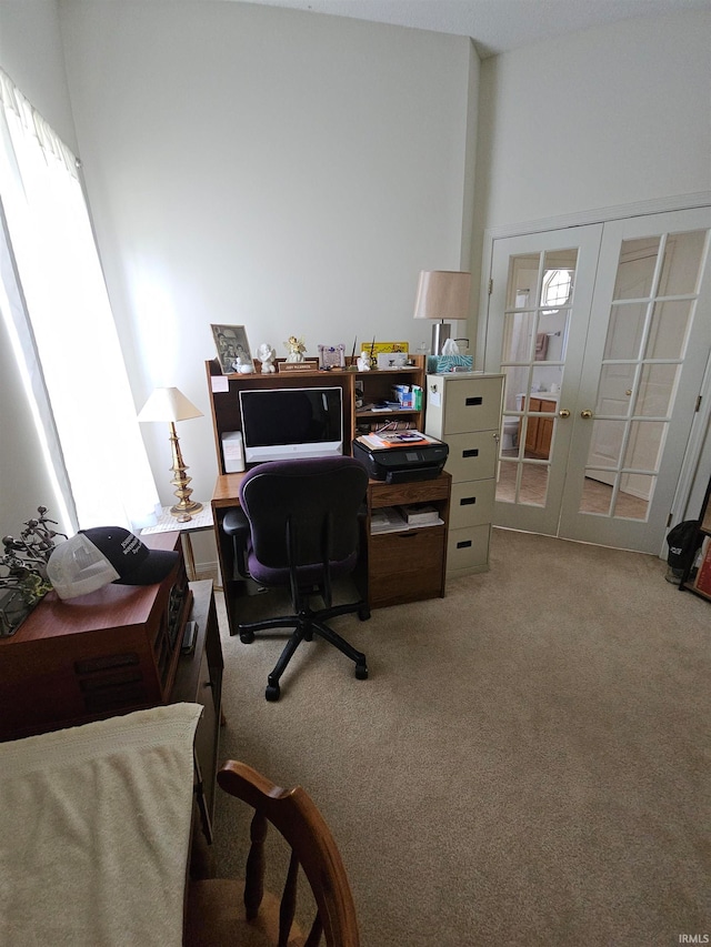 carpeted home office with a towering ceiling and french doors