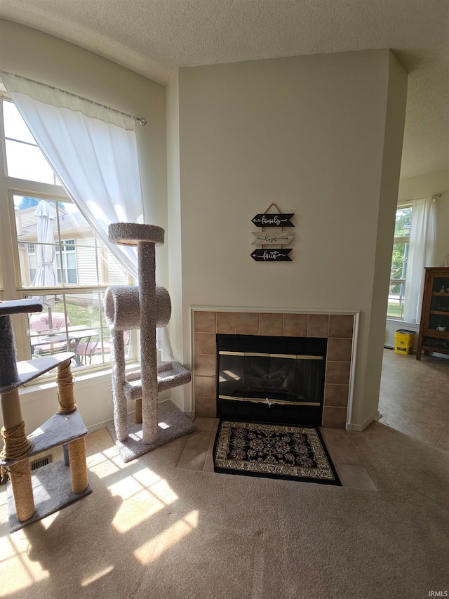 living room featuring a textured ceiling, a tiled fireplace, and light carpet