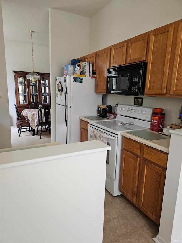 kitchen featuring a textured ceiling, hanging light fixtures, white appliances, and light tile patterned flooring