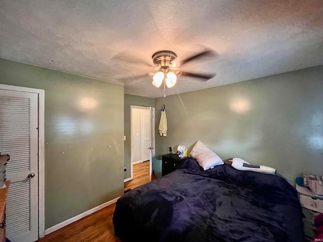 bedroom with a textured ceiling, ceiling fan, and hardwood / wood-style flooring