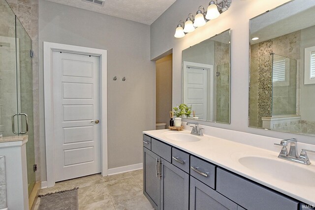 bathroom featuring a textured ceiling, vanity, tile patterned floors, and a shower with shower door