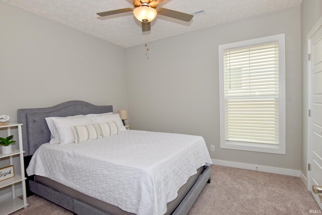 carpeted bedroom featuring ceiling fan and a textured ceiling