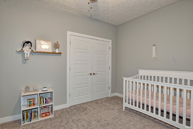 bedroom with carpet floors, a crib, a textured ceiling, and a closet