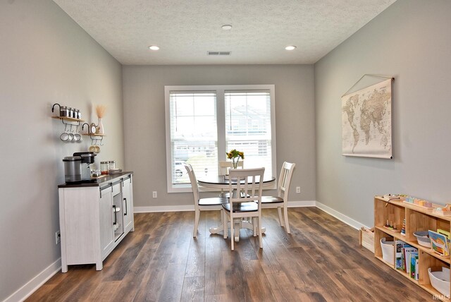 dining room with a textured ceiling and dark hardwood / wood-style floors