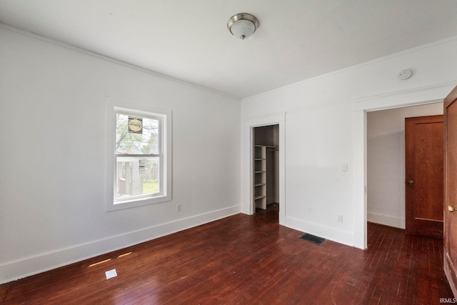 unfurnished bedroom featuring hardwood / wood-style flooring, crown molding, baseboards, and a closet