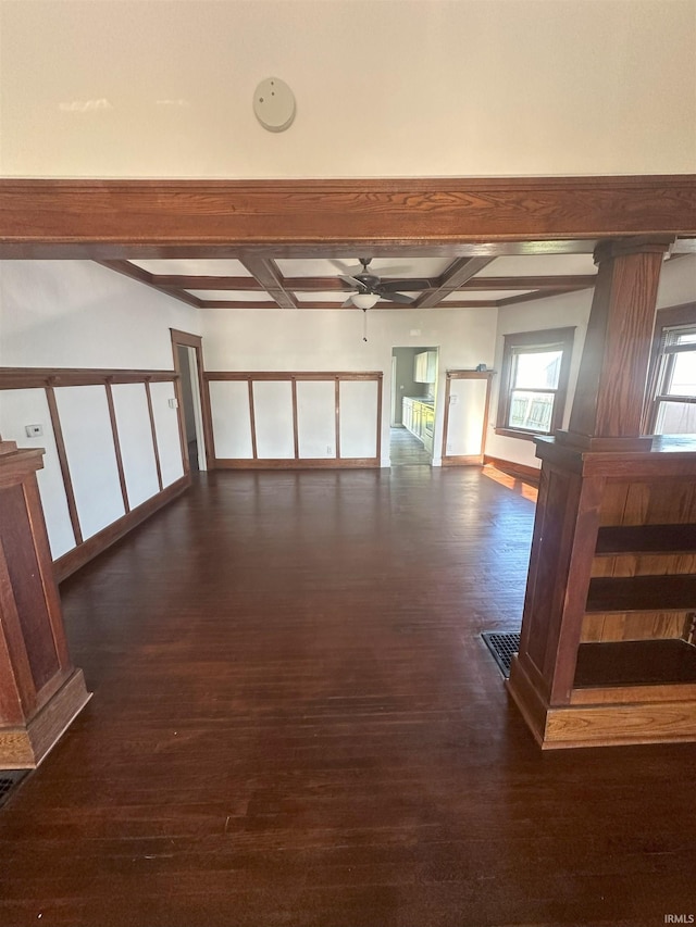 spare room with ornate columns, a ceiling fan, beamed ceiling, and wood finished floors