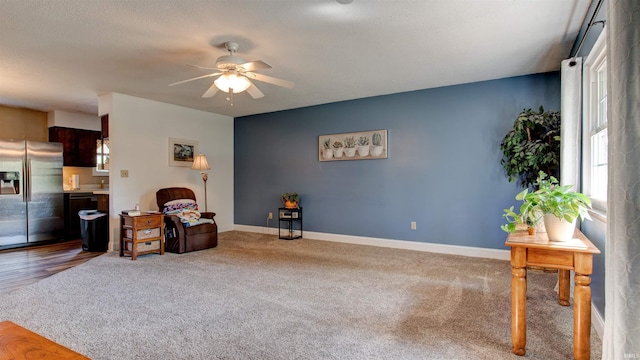 living area with carpet flooring, baseboards, and ceiling fan