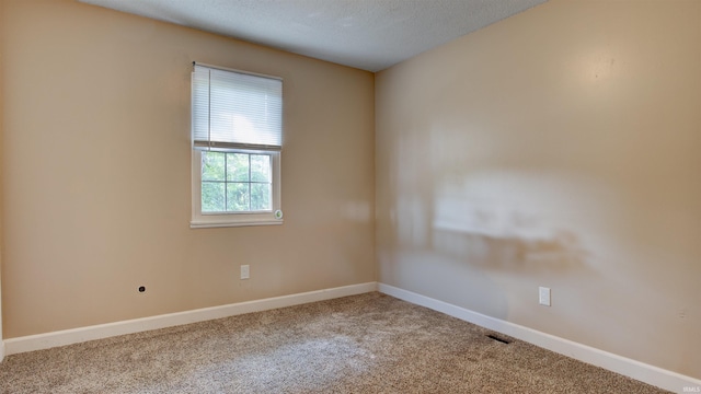 carpeted spare room featuring a textured ceiling and baseboards