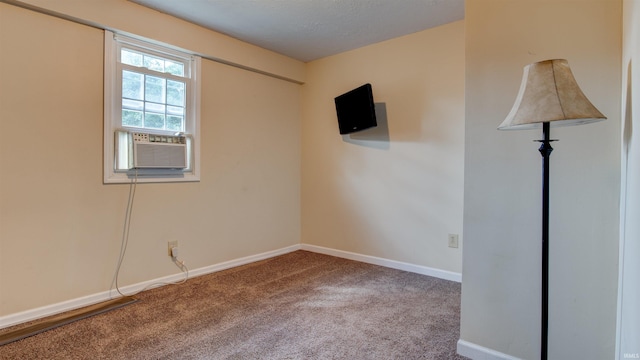 empty room with cooling unit, carpet floors, a textured ceiling, and baseboards