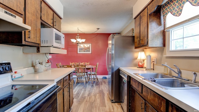kitchen featuring electric range, under cabinet range hood, a sink, light wood finished floors, and white microwave