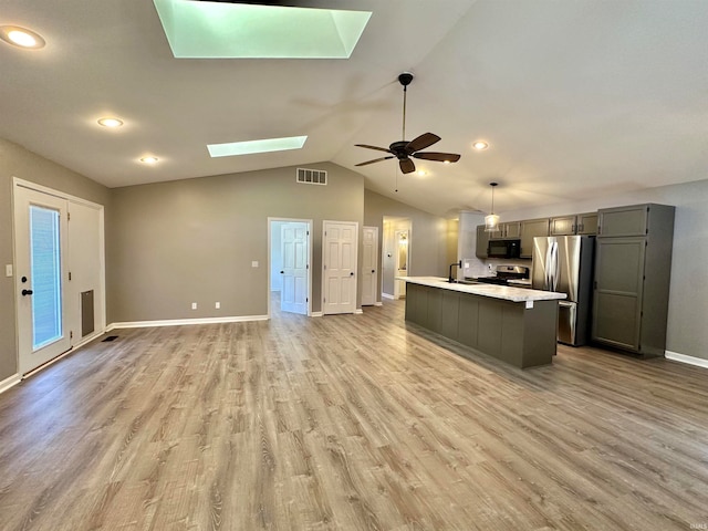 kitchen featuring vaulted ceiling with skylight, hardwood / wood-style floors, stainless steel appliances, ceiling fan, and gray cabinetry