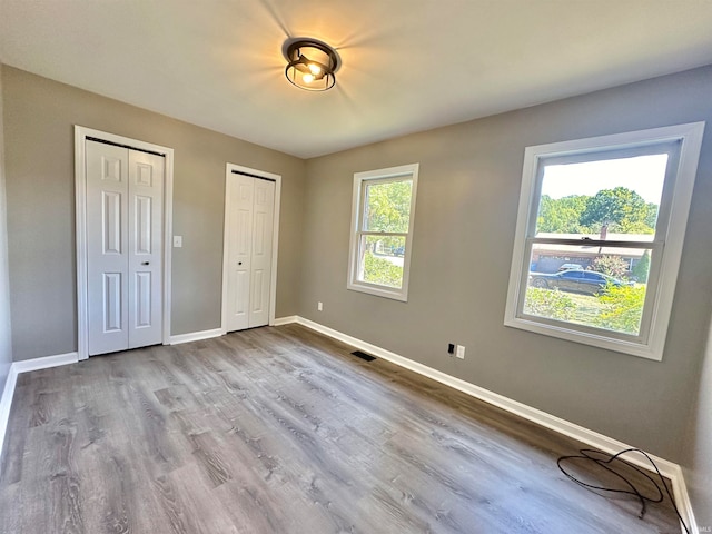 unfurnished bedroom featuring two closets and hardwood / wood-style flooring