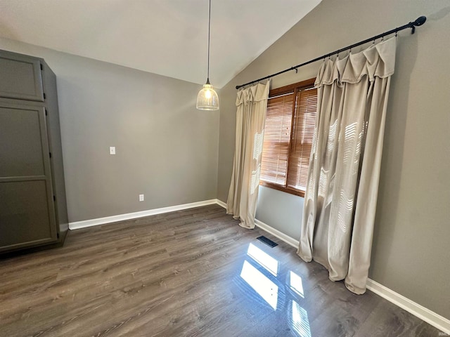 unfurnished dining area with vaulted ceiling and dark hardwood / wood-style flooring