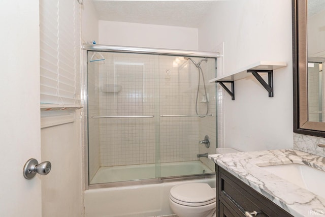 full bathroom with combined bath / shower with glass door, vanity, toilet, and a textured ceiling