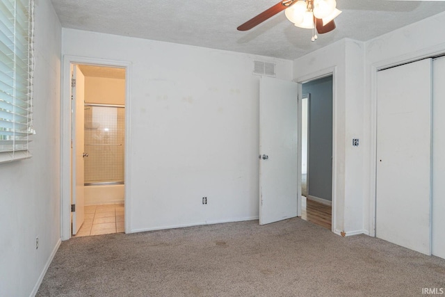 unfurnished bedroom featuring a textured ceiling, connected bathroom, ceiling fan, a closet, and carpet flooring