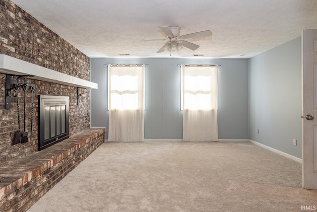 unfurnished living room with a textured ceiling, carpet flooring, ceiling fan, and a fireplace