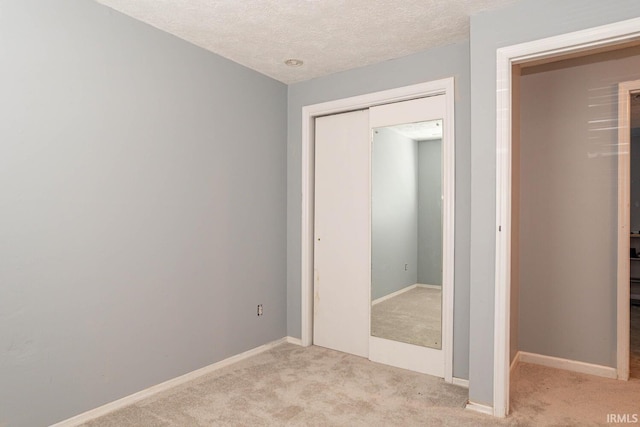 unfurnished bedroom with light carpet, a textured ceiling, and a closet