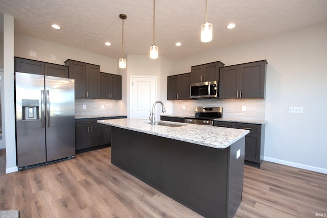 kitchen featuring light hardwood / wood-style floors, stainless steel appliances, a textured ceiling, and pendant lighting