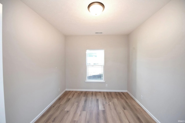 empty room with a textured ceiling and light wood-type flooring