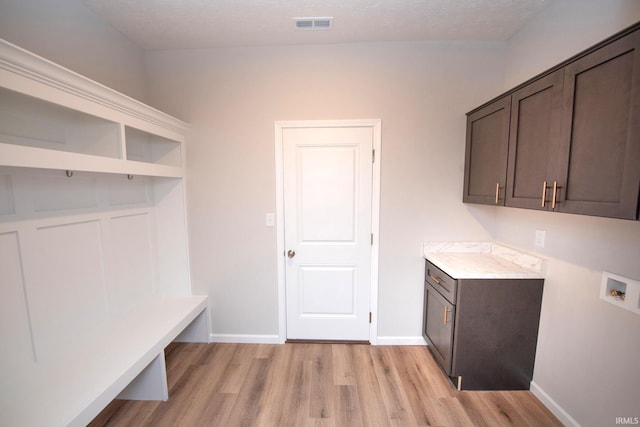 laundry area featuring cabinets, hookup for a washing machine, a textured ceiling, and light wood-type flooring