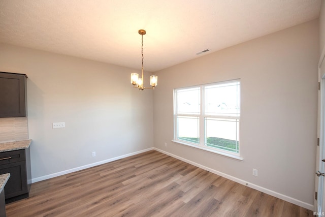 unfurnished dining area with hardwood / wood-style flooring and a chandelier