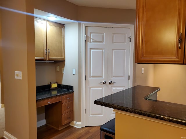 kitchen featuring dark stone countertops, hardwood / wood-style flooring, and built in desk