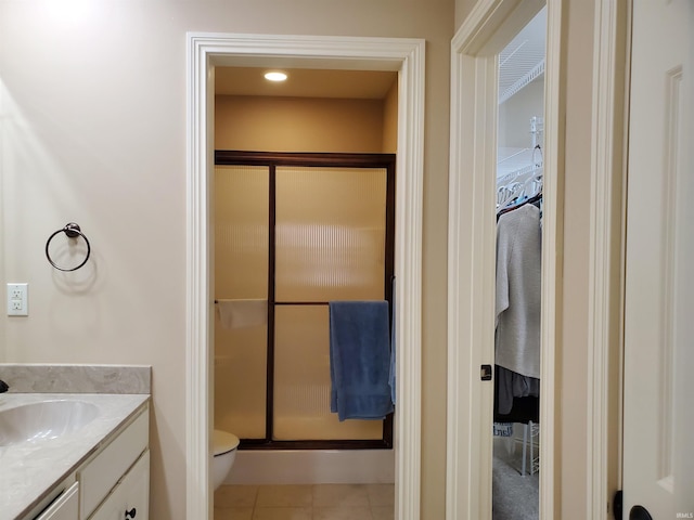 bathroom with a shower stall, toilet, vanity, and tile patterned floors