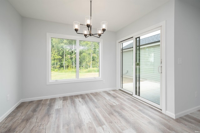 empty room with a notable chandelier and light hardwood / wood-style floors