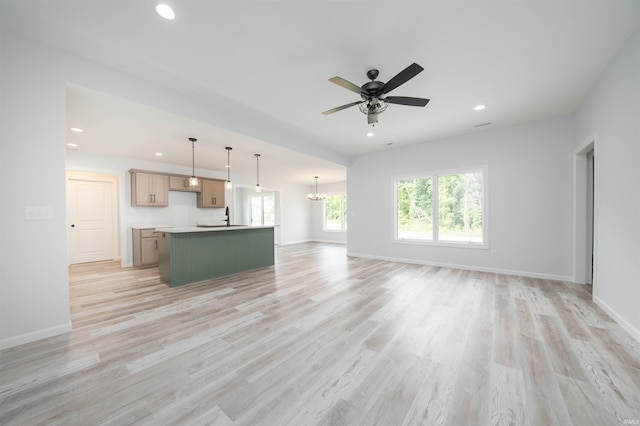 unfurnished living room featuring ceiling fan, sink, and light hardwood / wood-style floors