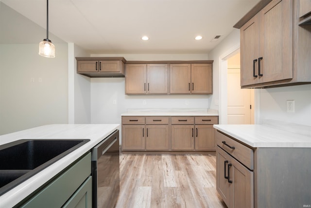 kitchen featuring stainless steel dishwasher, decorative light fixtures, and light hardwood / wood-style flooring