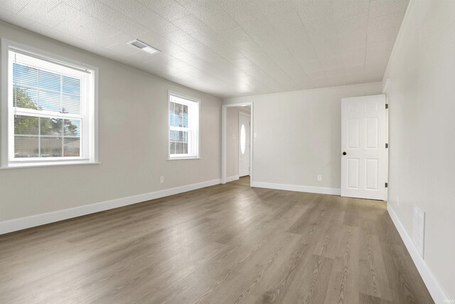 spare room with wood-type flooring and a healthy amount of sunlight