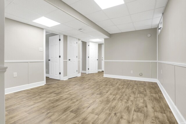 basement with a paneled ceiling and wood-type flooring