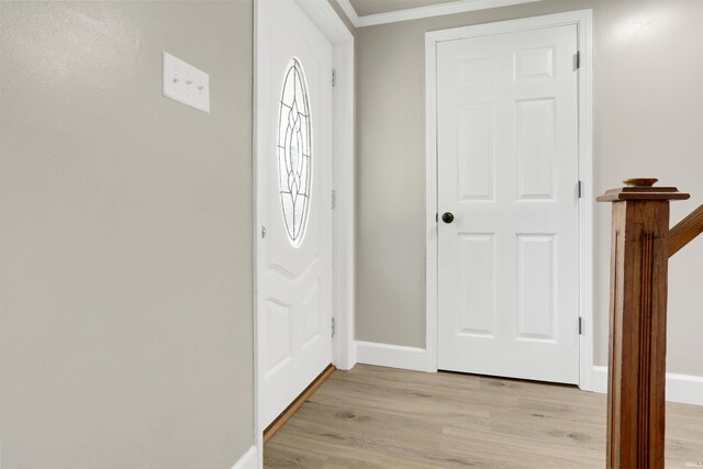 foyer entrance featuring crown molding and light wood-type flooring