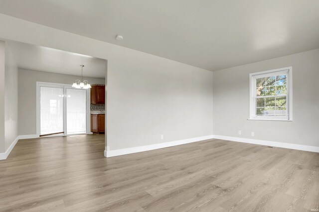 spare room featuring light hardwood / wood-style flooring and an inviting chandelier