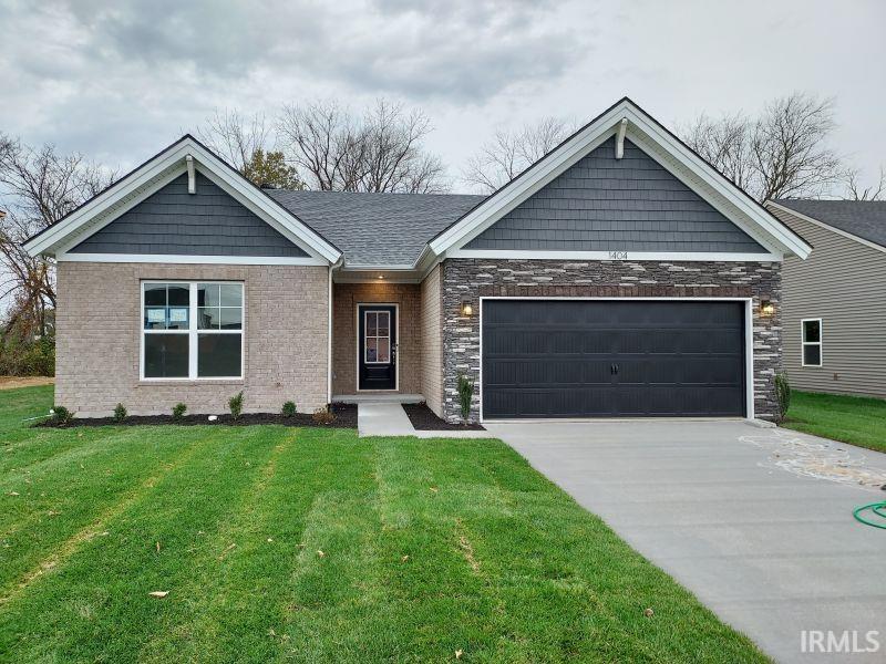 view of front facade with a garage, brick siding, driveway, and a front lawn